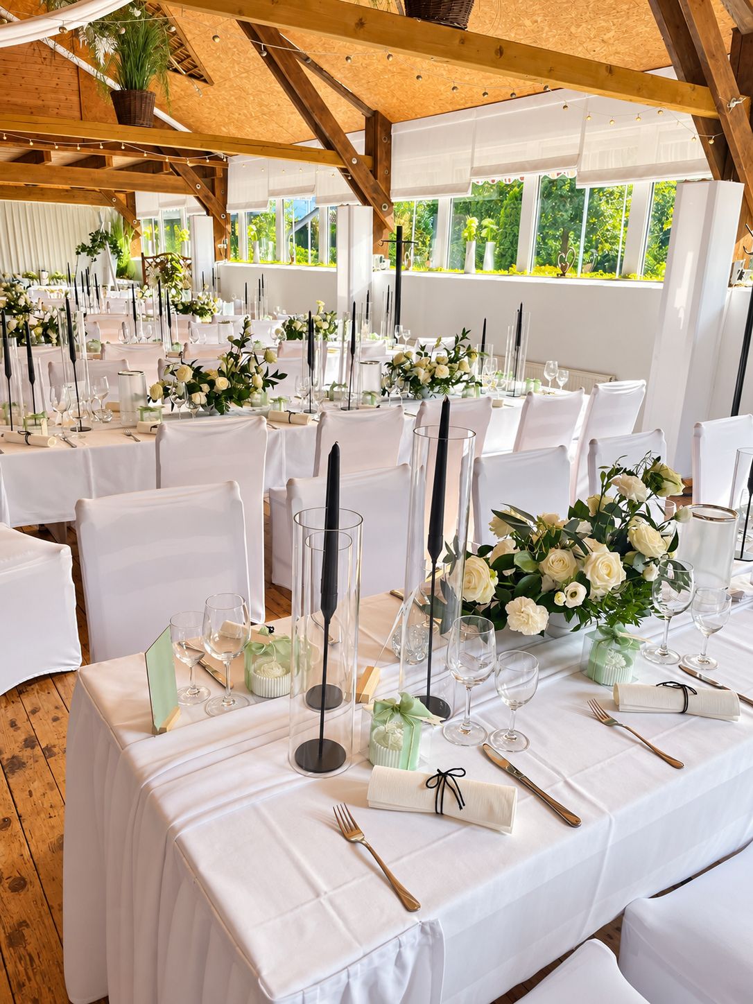 Hochzeitstafel mit weißen Rosen und schwarzen Kerzenleuchtern